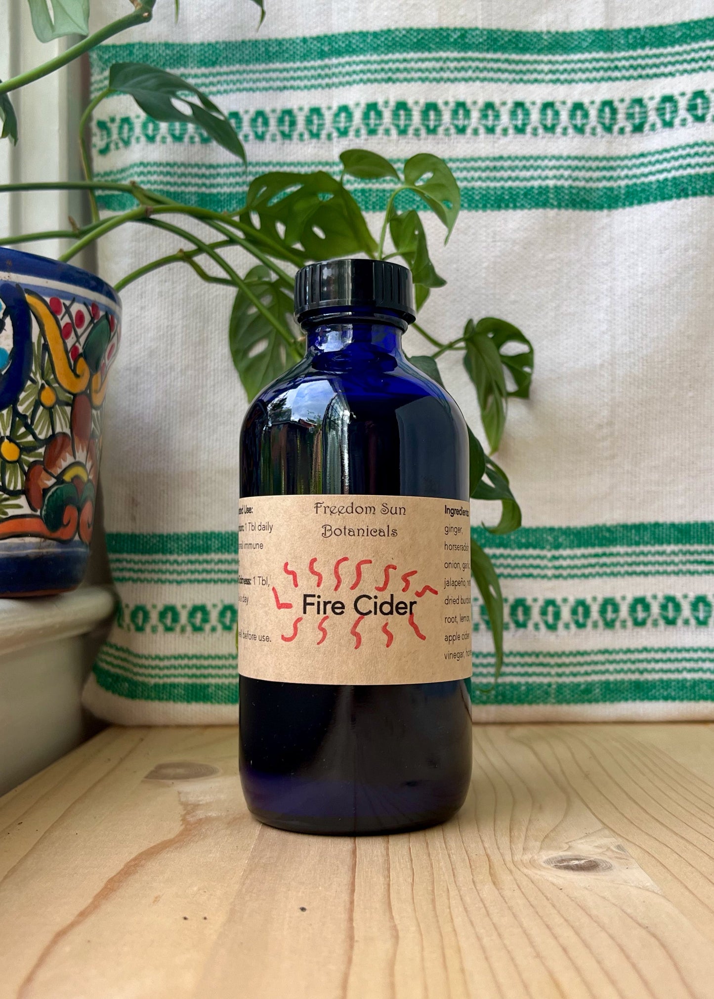 Bottle of Fire Cider on wood surface with decorative items