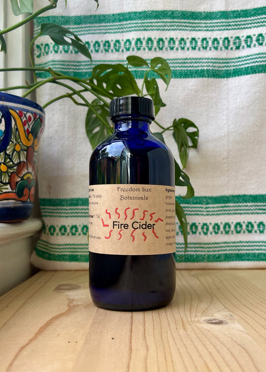 Bottle of Fire Cider on wood surface with decorative items