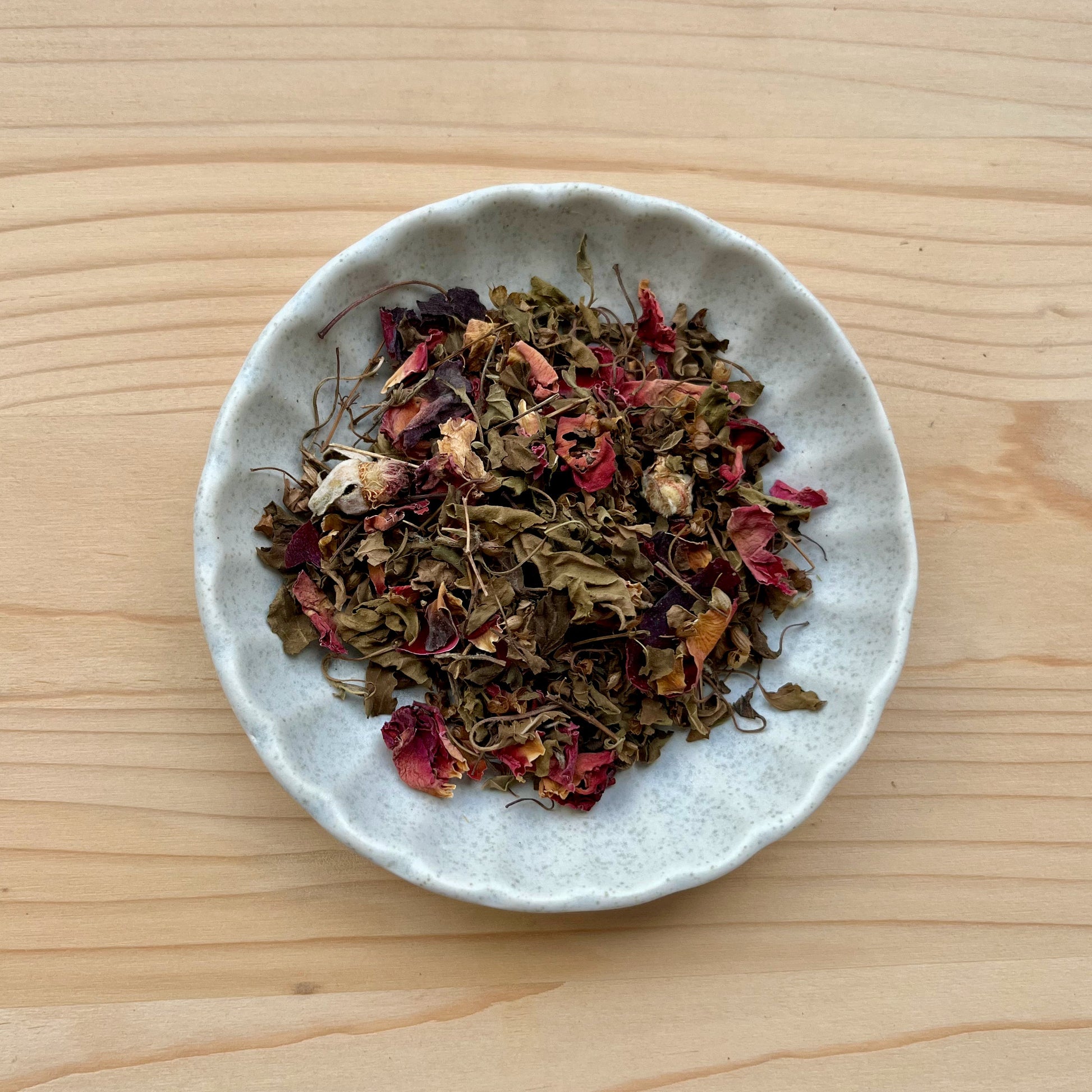 Small bowl of dried herbs on a wooden surface
