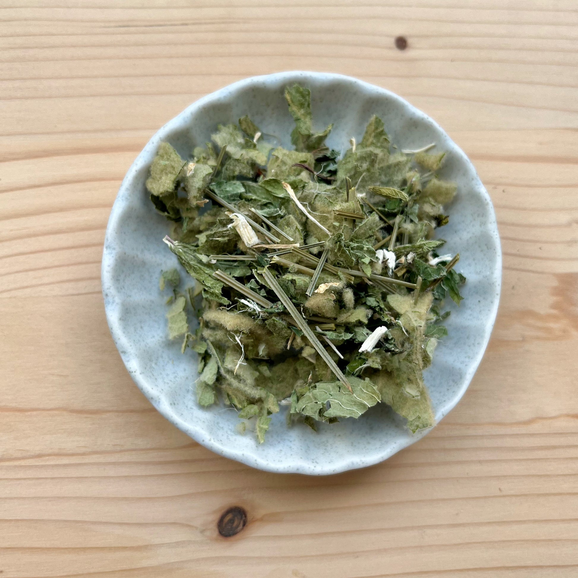 Small bowl of green leafy substance on a wooden surface