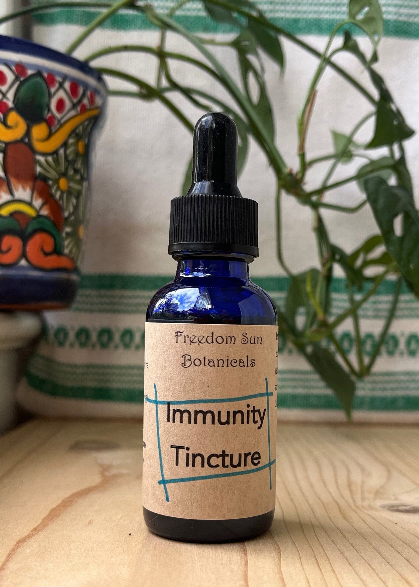 Bottle of Immunity Tincture with a dropper on a wooden surface, with decorative elements in the background.