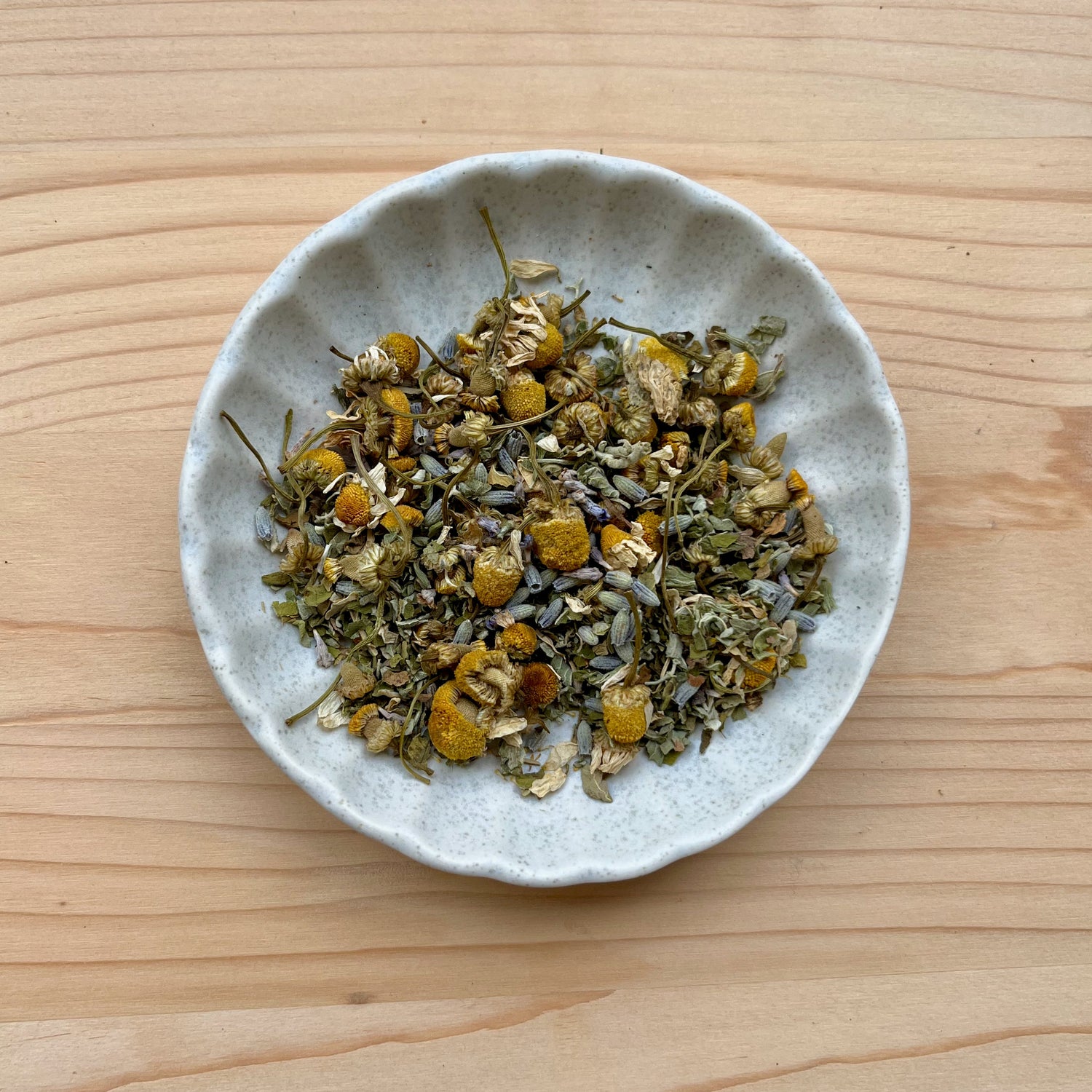 Small bowl of dried herbs on a wooden surface