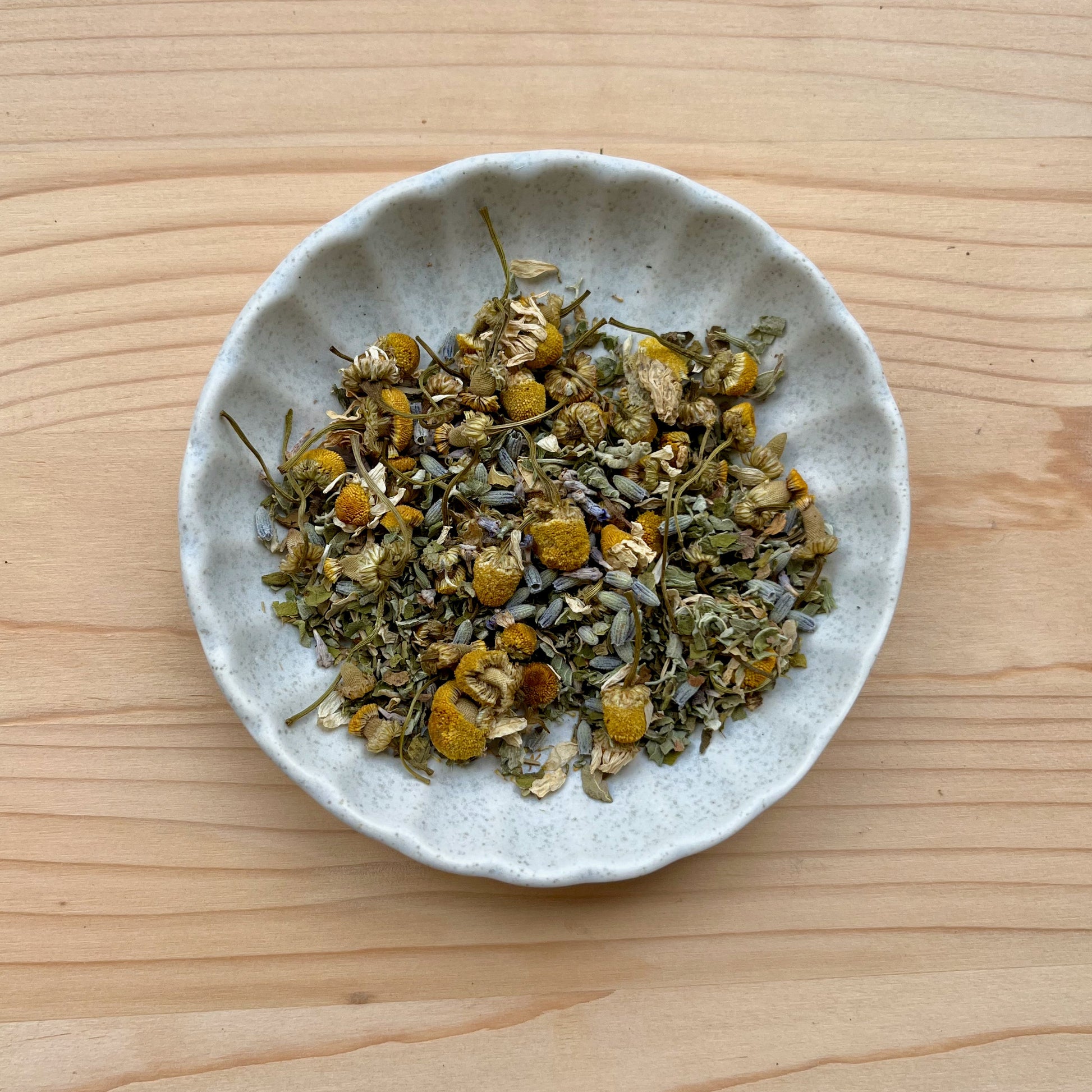 Small bowl of dried herbs on a wooden surface